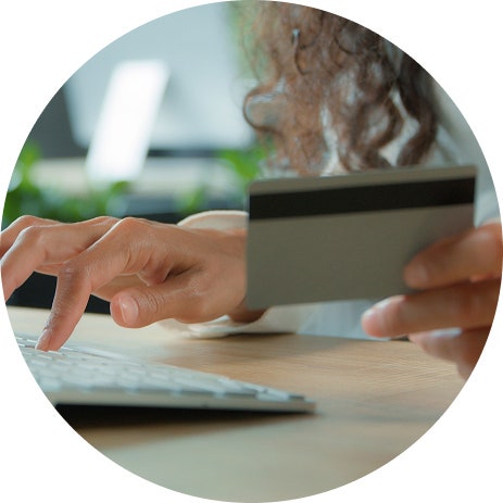 Individual holding a credit card while on the computer